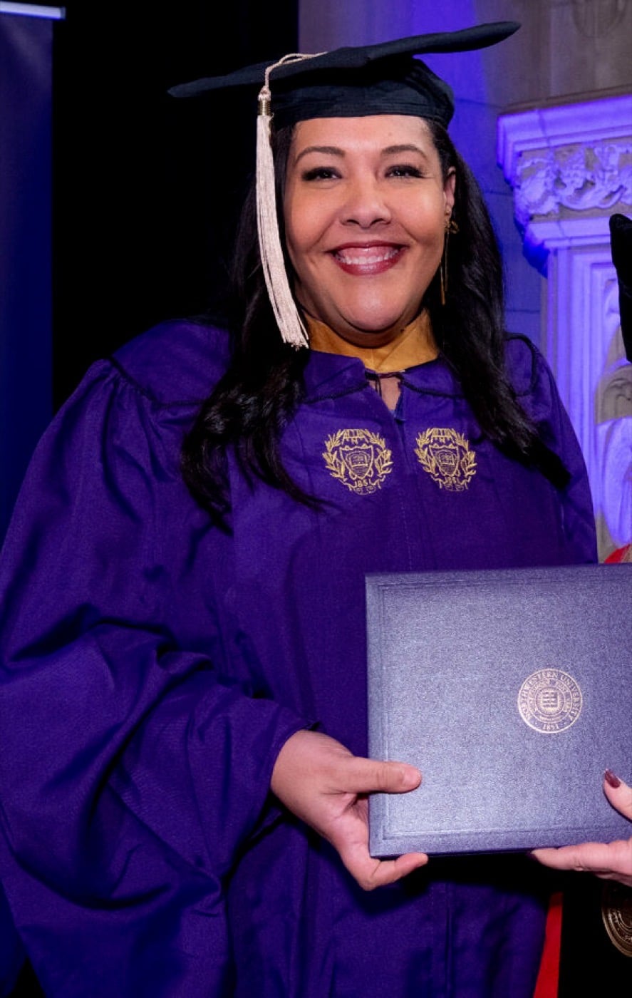 Amanda Matchett in graduation regalia, holding her diploma from Northwestern University